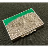 A silver and enamel rectangular snuff box, the cover embossed with Haddon Hall, picked out in green,