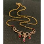 An Edwardian diamond and ruby necklace, the scrolling floral body set with five vibrant red rubies