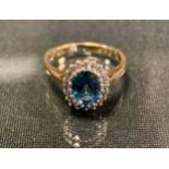 A diamond and blue topaz ring, central oval vibrant pale blue topaz approx 0.75ct surrounded by