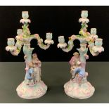 A pair of German four-light three branch figural candelabra, encrusted with flowers, the columns