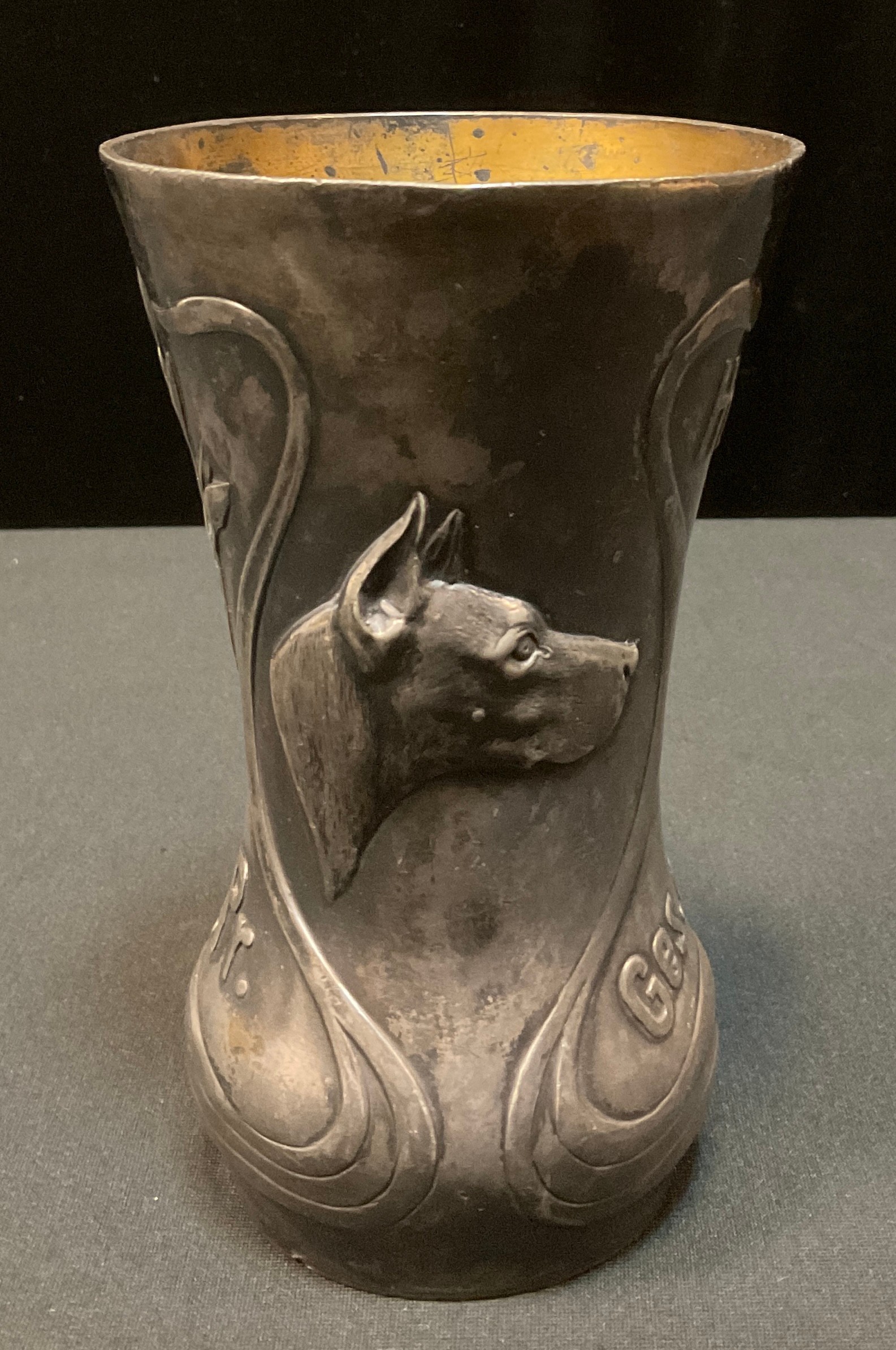 An early 20th century German pewter waisted cylindrical vase, embossed with sinuous scrolls, flowers