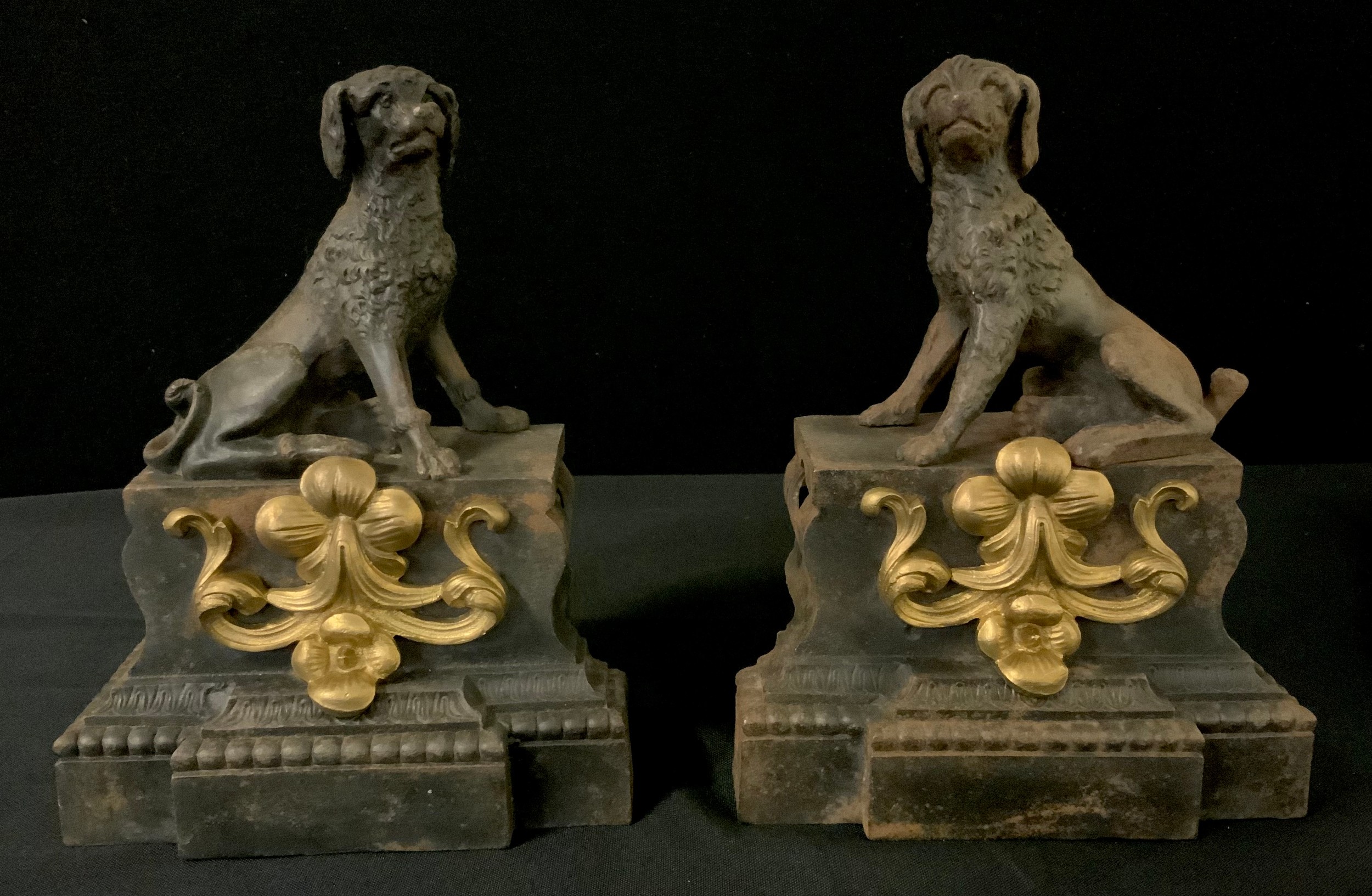 A pair of French cast iron chenets, cast with Poodles, on a shaped rectangular pedestal, applied