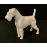 A Meissen Terrier, by Erich Oehme, signed, in the white, 14cm high, crossed swords