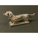 A 20th century silver plated car mascot, as a Long Haired Dachshund, rectangular base, 7cm high