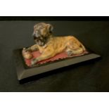 A late 19th century cold painted model, of an English Mastiff, reclining, with a bone, black