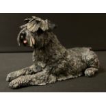 An Eve Pearce model of Schnauzer reclining, 20cm long, painted initials