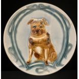 An early 20th century majolica circular plate, in relief with Pug, seat, within sinuous strapwork,