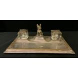 An early 20th century silver plated desk stand, with two wells, centred by a large Bulldog, the base