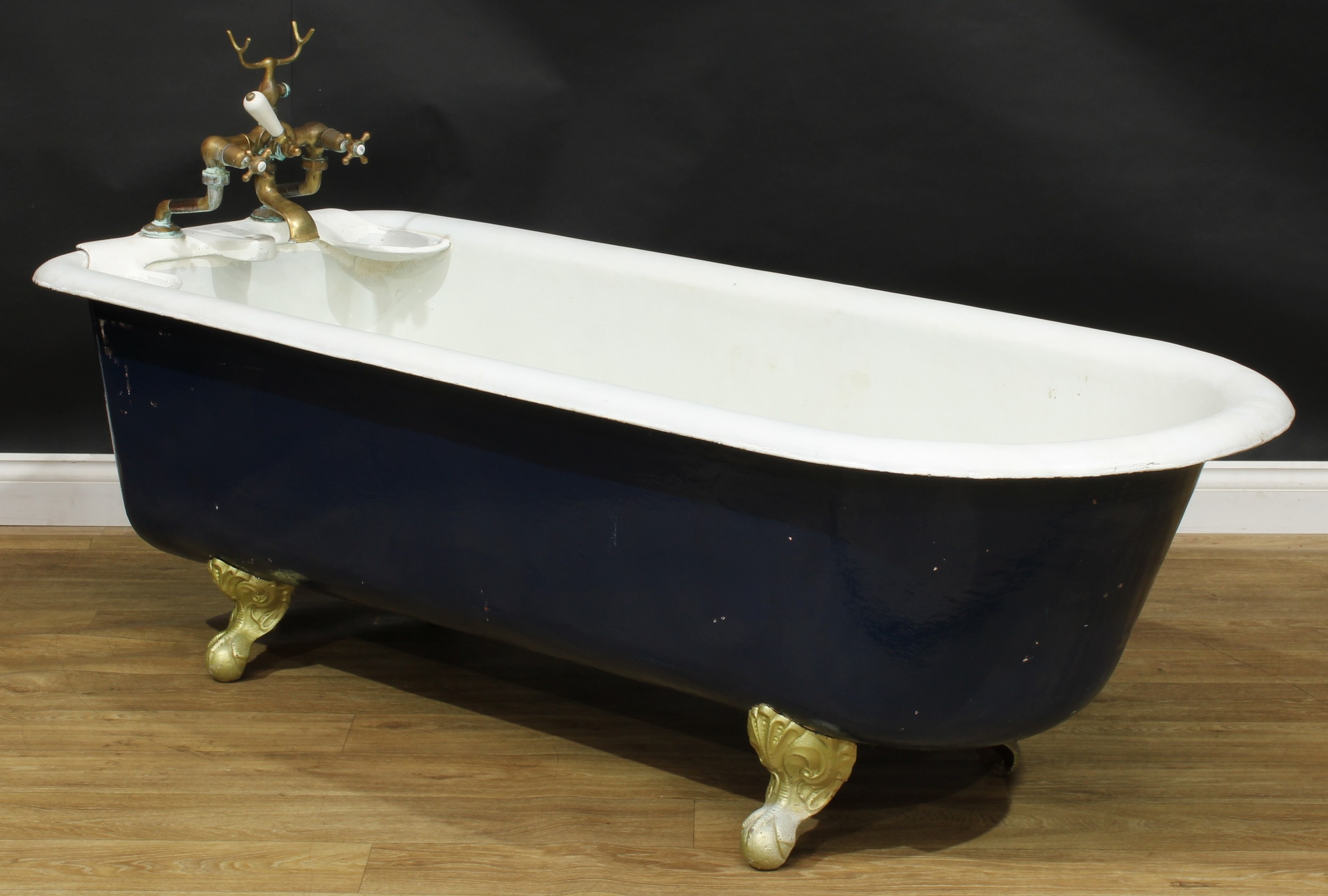 An early to mid-20th century cast iron roll top bath, ball and claw feet, 58cm high excluding