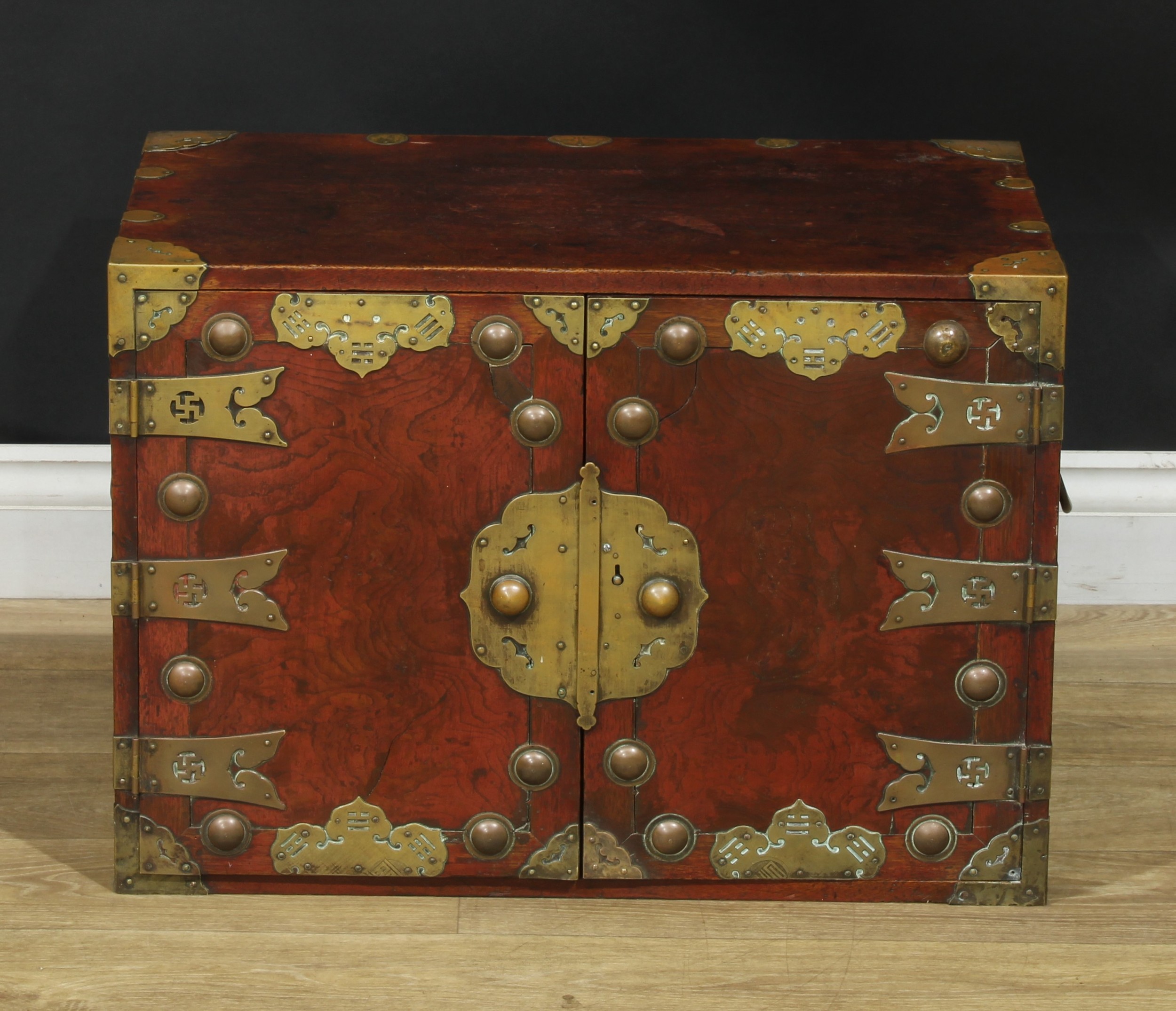 A Chinese brass mounted enclosed table cabinet, flush rectangular top above a pair of yumu veneer