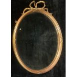 A 19th century giltwood oval looking glass, the bevelled mirror plate crested by a draped and tied