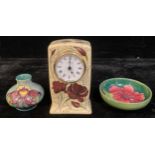 A Moorcroft mantel clock; a Moorcroft Hibiscus pattern trinket bowl; a Moorcroft vase (3)