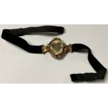 A Victorian mourning choker, the gold plated oval swivel centrepiece applied with an arrangement