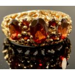 A 9ct gold and garnet three stone ring, the faceted oval cut stones graduating, fancy shank