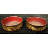 A pair of Regency red lacquer and gilt circular ogee bottle coasters, decorated with fruiting vines,