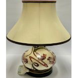 A Moorcroft compressed ovoid table lamp, tube lined with orchids and scrolling fronds, in shades