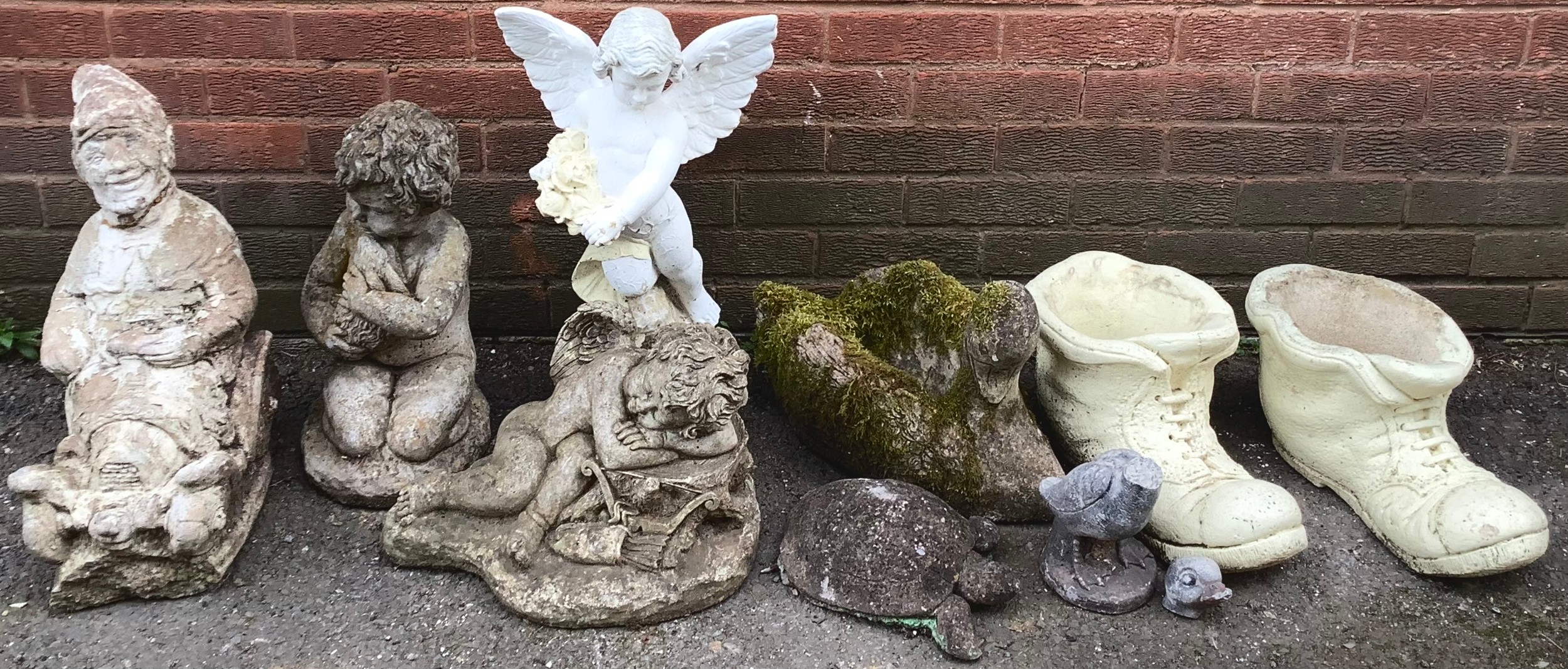 A collection of reconstituted stone garden ornaments including a gnome, a winged cherub, a