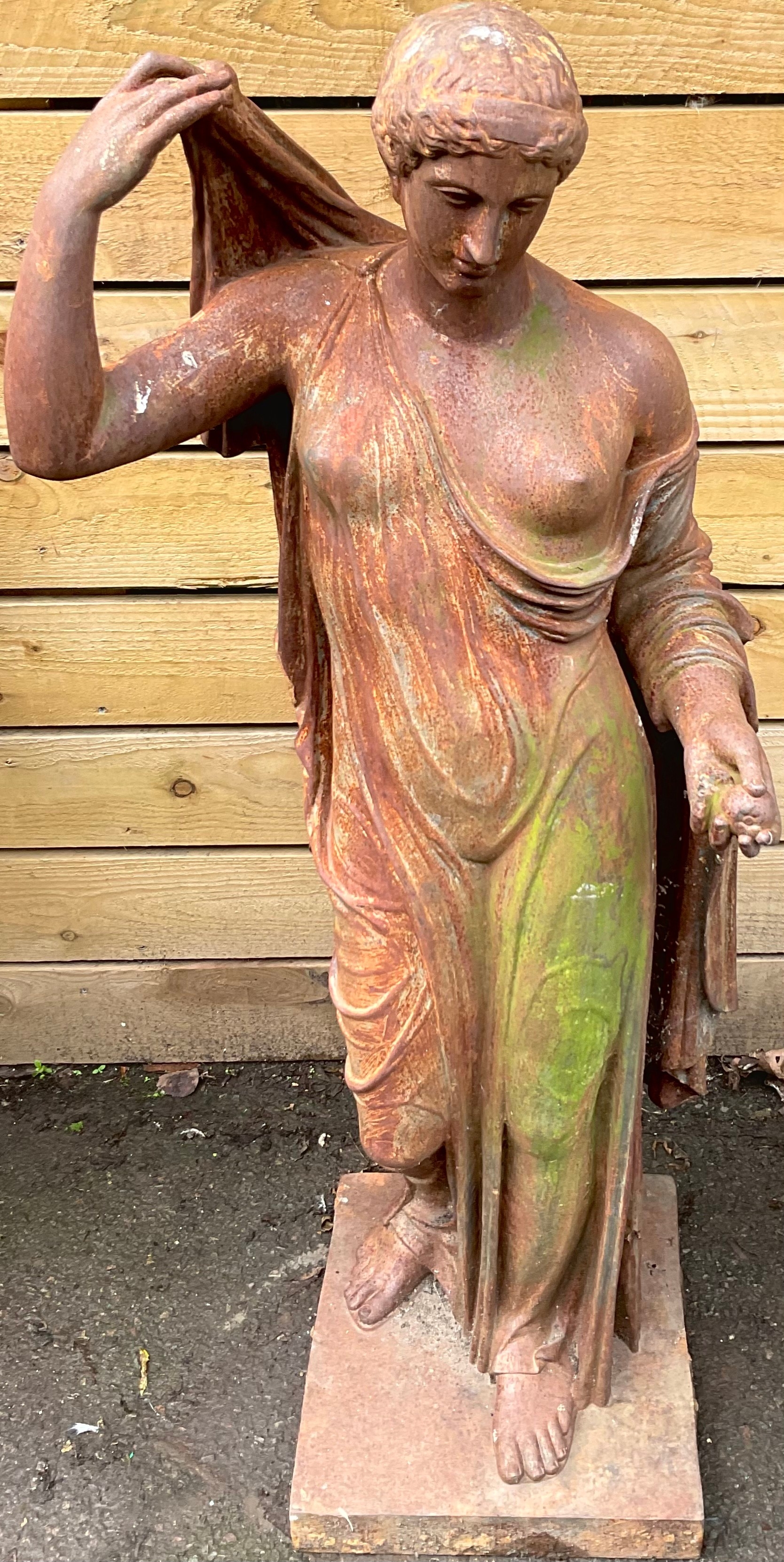 A cast iron garden stature, of a Greek lady, wearing flowing robes, holding a fruit, 128cm high