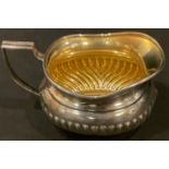 A George V silver boat shaped milk jug, stop fluted, angular reeded handle, gilded interior,