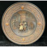 A late 19th century German wall charger, in relief with a tavern scene, the border with shields