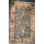 A Middle Eastern woollen rug or carpet, stylised flowers and foliage in shades of green, red and