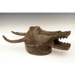 A Senufo Waniugo helmet mask, carved with warthog tusks, crocodile jaws and antelope horns, 78cm