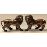 A pair of bronzed metal lions, each approximately 32cm long