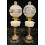 A pair of early 20th century oil lamps, milk glass fonts, brass columns, ebonised wooden bases,