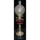 A 19th century oil lamp, frosted globular shade, ruby glass font, brass columnar support,