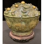 A Chinese bronzed metal fortune or treasure bowl, decorated with dragons and bats, on hardwood