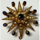 An unmarked metal metamorphic starburst brooch/pendant, set with graduated seed pearls and blue