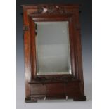 An Art Nouveau period oak looking glass, bevelled mirror place, the frame carved with stylised