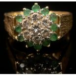 An 18ct gold emerald and diamond cluster ring, size T, textured bark shank, London 1976, 8g