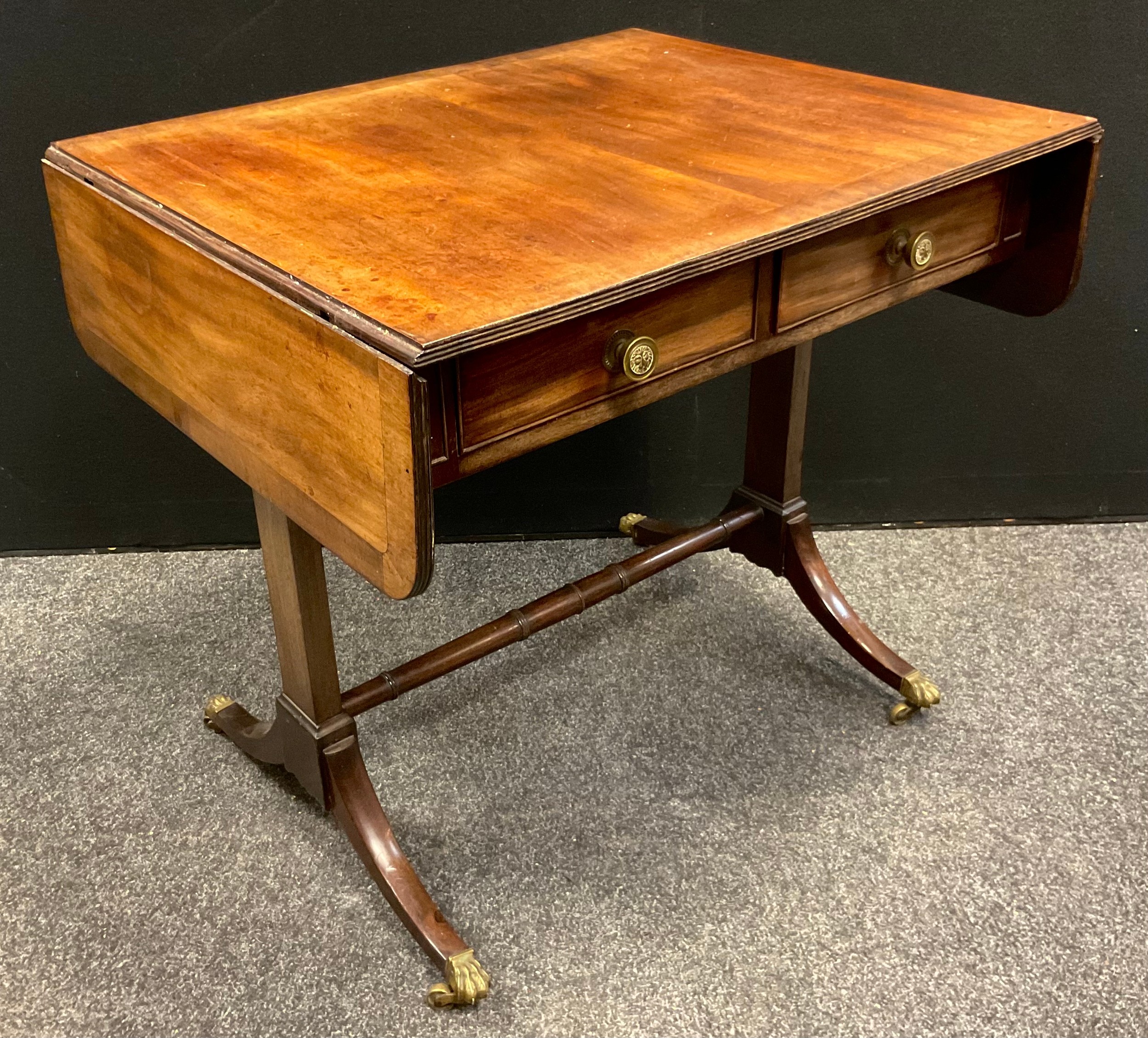 A George III mahogany sofa table, rounded rectangular over-sailing top with reeded edge, pair of