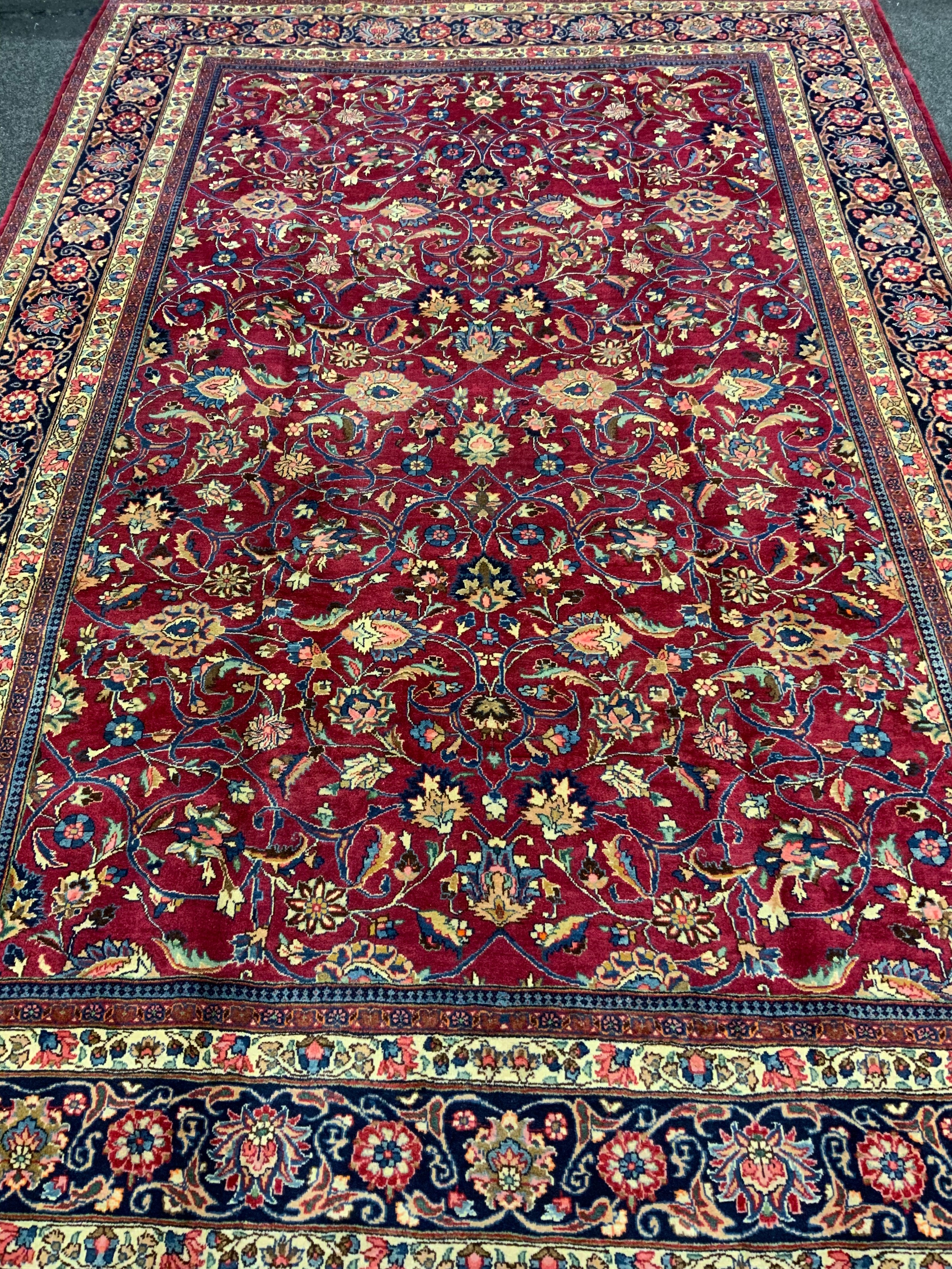 A Persian Tabriz hand-knotted rug / carpet, the field in rich red with scrolling tendrils of - Image 2 of 4