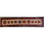 A Persian Karajah woollen runner, ten shaped multicoloured medallions, in tones of red, ochre,