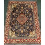 A Persian Kashan carpet, the diamond-shaped medallion within a field of scrolling flowering stems,