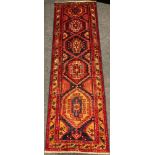 A North West Persian Heriz runner carpet, hand-knotted in rich tones of red, blue, and ochre, with a