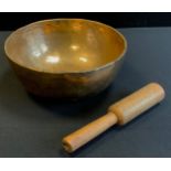 A Chinese/Tibetan brass singing bowl and wooden baton, plain banded body, 9.7cm high, 24cm diameter