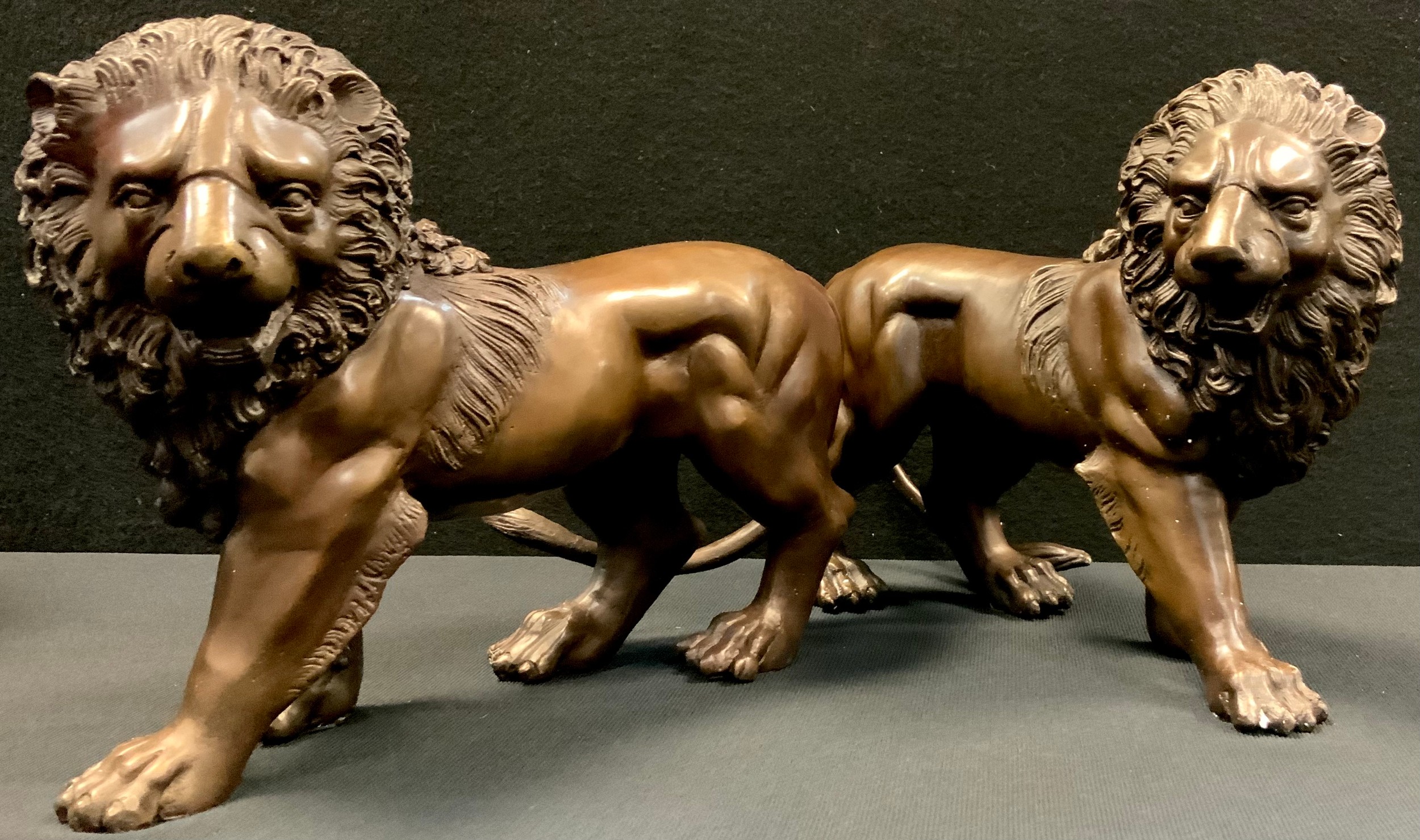 A pair of bronzed metal figures, Walking Lions, each 33cm long (2)