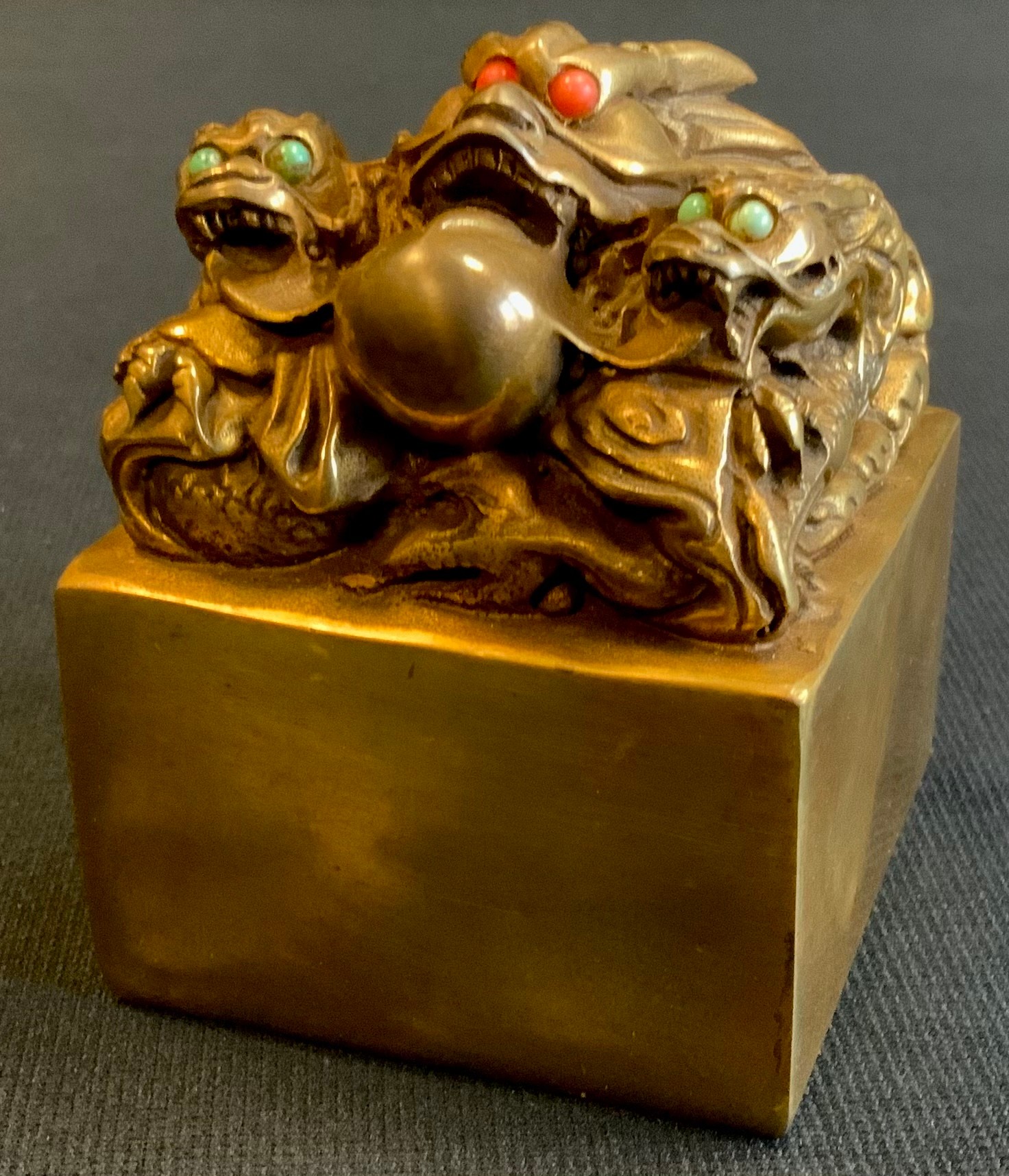 A modern gilt bronzed metal Chinese dragon seal, with green and red cabochon eyes, 10cm x 7cm