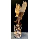 A large carved wooden sculpture, Golden Eagle with eaglet, wings outstretched, resting on a stump,