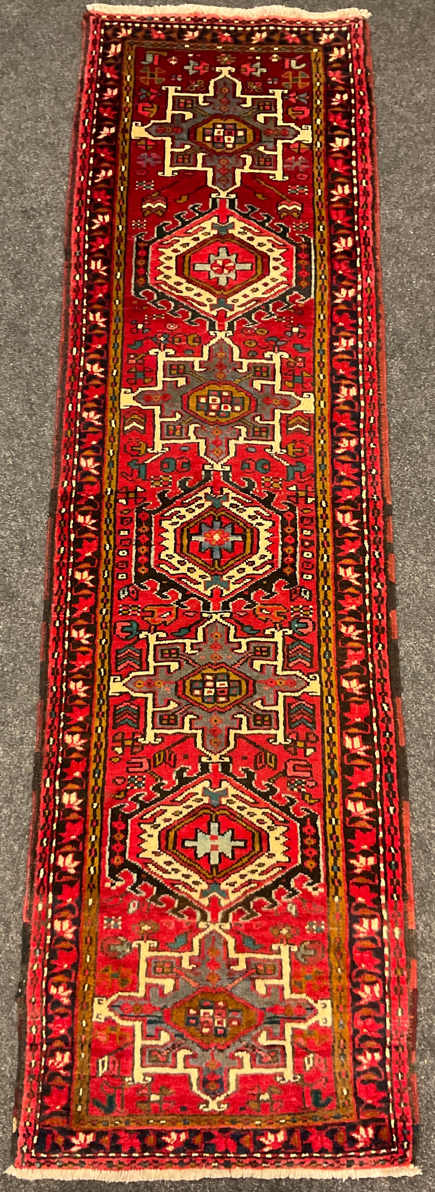 A North West Persian Heriz runner, hand-knotted in tones of red, black, blue, and cream, 275cm x