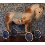 A large straw-filled cream and brown mohair ride-on or push along Horse on wheels, felt saddle, pull