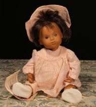 A Götz Sasha Morgenthaler baby doll with dark brown hair, wearing a pink and white dress with