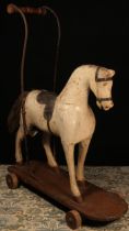 A late 19th century child's push along Horse on wheels, the carved wooden Horse painted white with