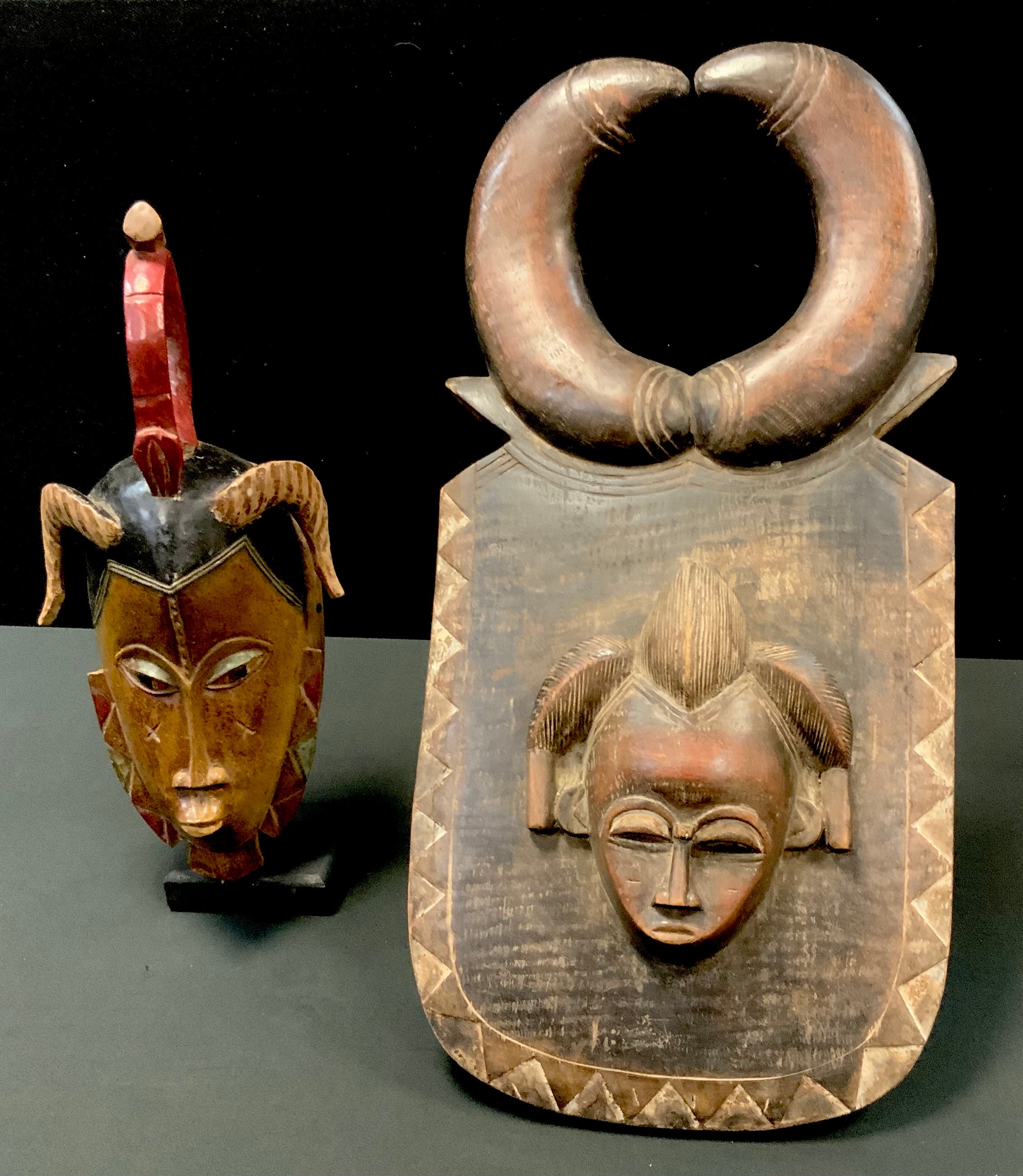 An African Dan deangle headdress mask, carved face, adorned with metal nose piece and cowrie shells,