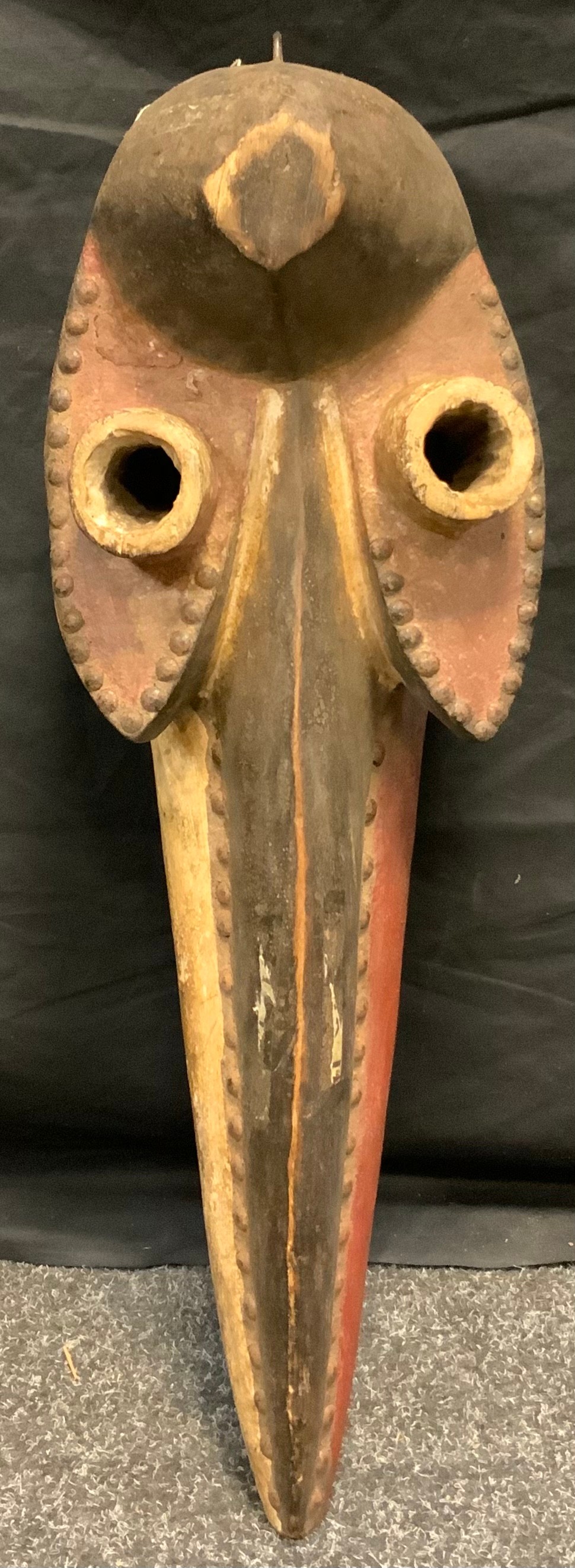 An African tribal zoomorphic dan bird mask, hole eyelets, elongated beak, nailed details, picked out