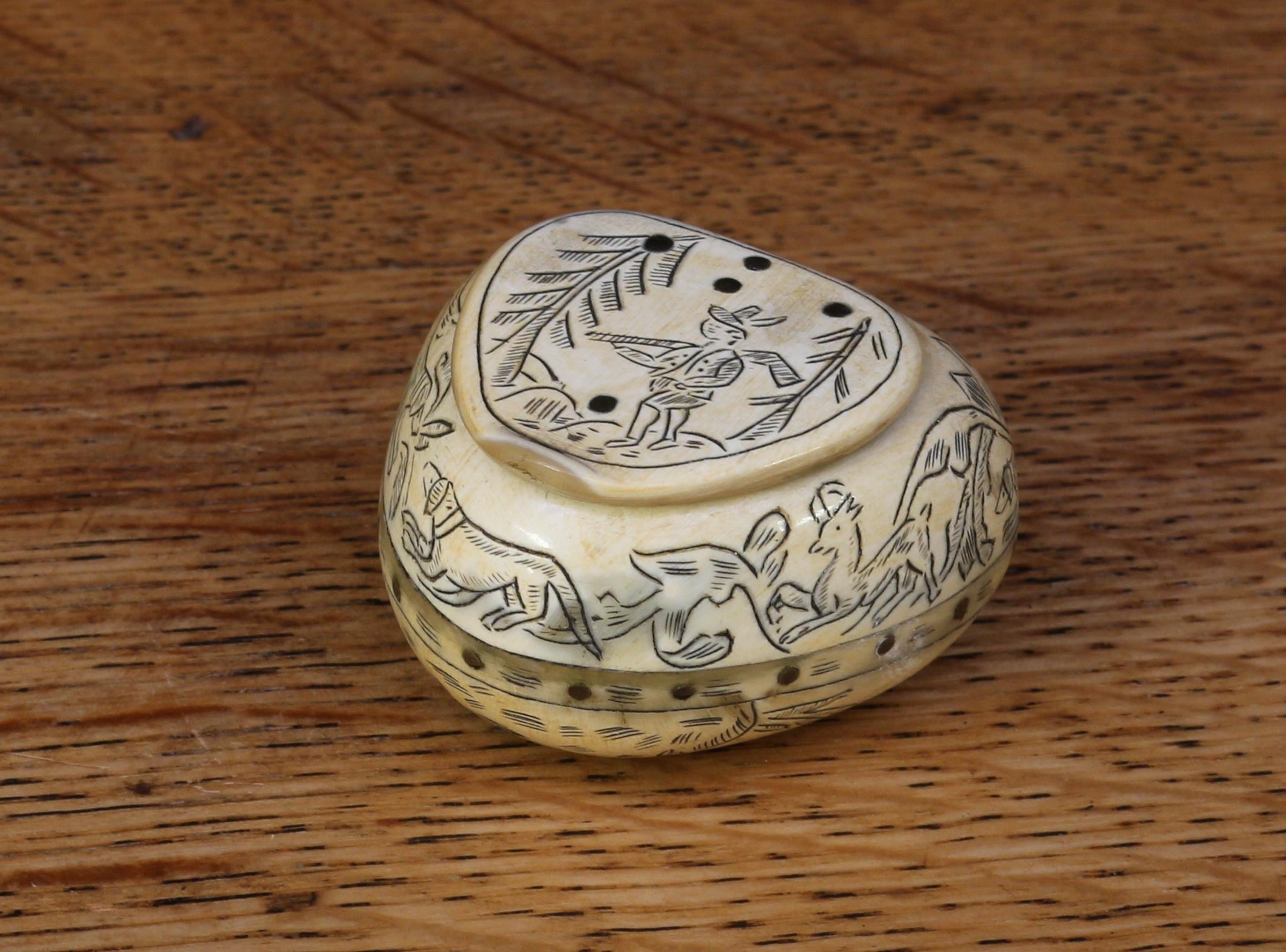 A scrimshaw horn heart shaped snuff box, engraved overall with a hunting scene, 4cm wide