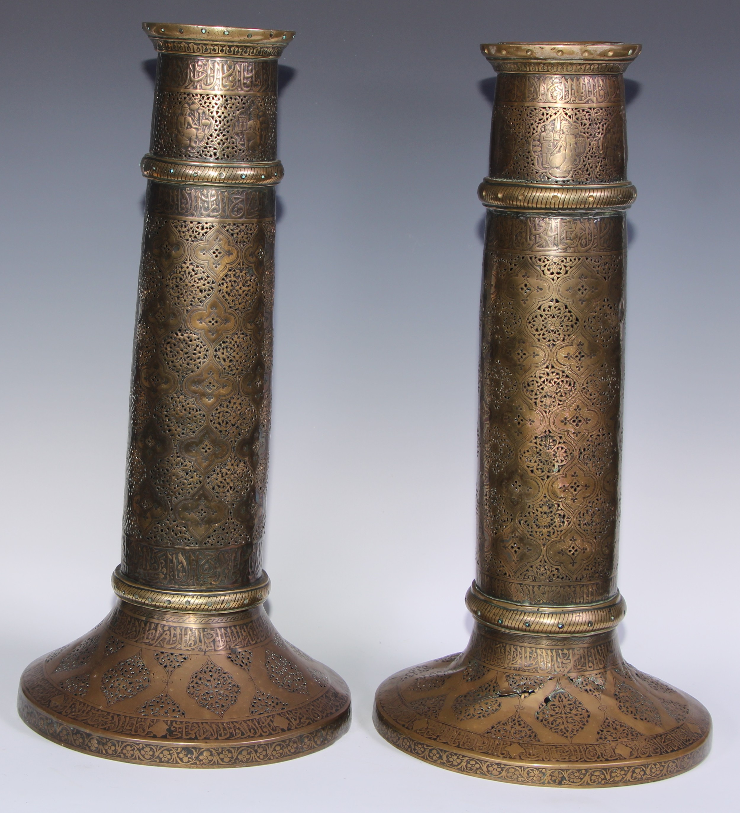 A pair of large Middle Eastern Islamic brass mosque candlesticks, pierced and engraved with a field